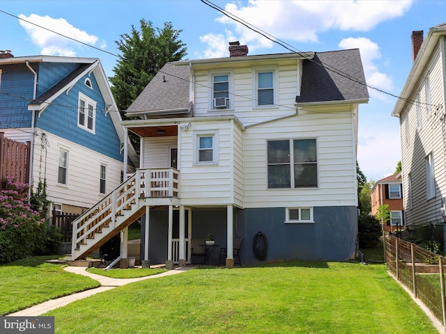 rear view of property featuring stairway, a chimney, fence, and a yard