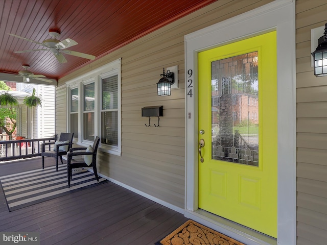 view of exterior entry featuring a porch and a ceiling fan