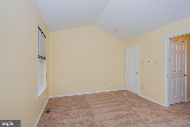 interior space featuring vaulted ceiling, baseboards, visible vents, and light colored carpet