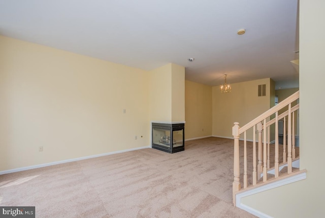 empty room featuring a notable chandelier, light colored carpet, visible vents, stairway, and baseboards