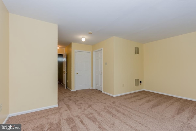 spare room featuring light carpet, visible vents, and baseboards