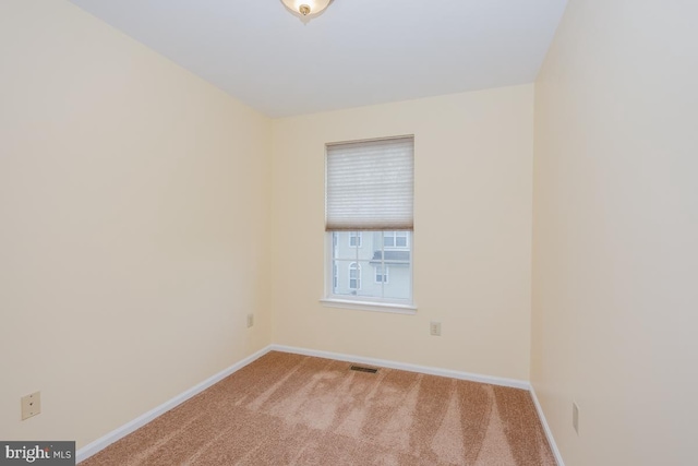 unfurnished room with light carpet, visible vents, and baseboards