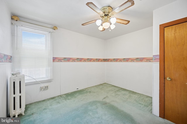 unfurnished room with carpet floors, plenty of natural light, radiator, and a ceiling fan