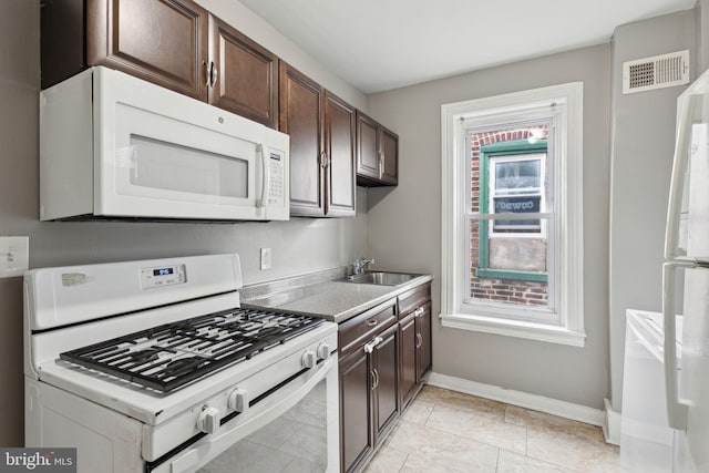 kitchen with white appliances, visible vents, a sink, and dark brown cabinets