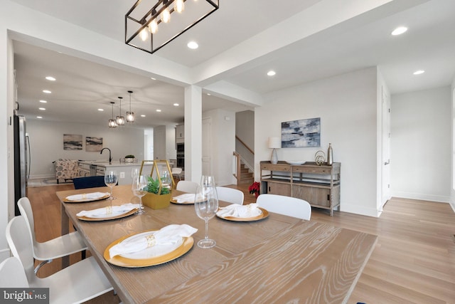 dining room featuring light wood finished floors, a barn door, baseboards, stairway, and recessed lighting