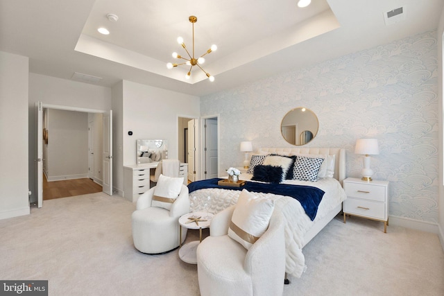 bedroom featuring light carpet, a tray ceiling, baseboards, and wallpapered walls