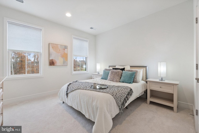 bedroom featuring light carpet, multiple windows, visible vents, and baseboards