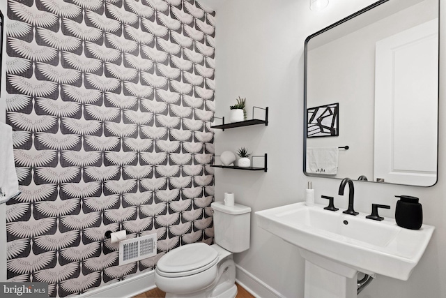 bathroom featuring baseboards, a sink, and toilet