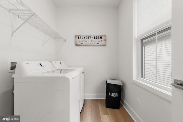 clothes washing area featuring laundry area, light wood-style flooring, baseboards, and washer and clothes dryer