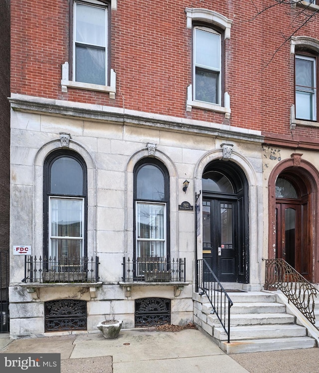 view of exterior entry featuring stone siding and brick siding