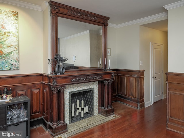 living room featuring a fireplace with flush hearth, dark wood finished floors, a wainscoted wall, and crown molding