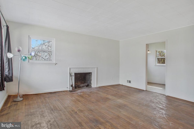 unfurnished living room featuring visible vents, a fireplace, and hardwood / wood-style flooring