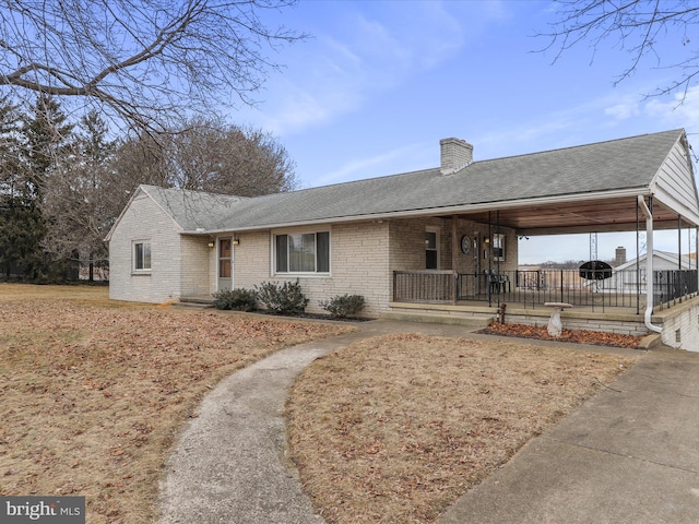 ranch-style house featuring brick siding, a chimney, a porch, a shingled roof, and a carport