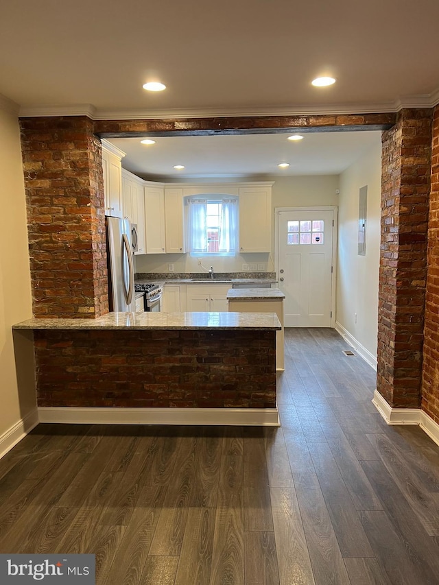 kitchen with a peninsula, dark wood-type flooring, white cabinets, appliances with stainless steel finishes, and light stone countertops