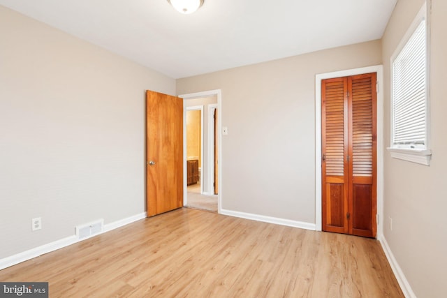 unfurnished bedroom with light wood-style floors, baseboards, visible vents, and a closet