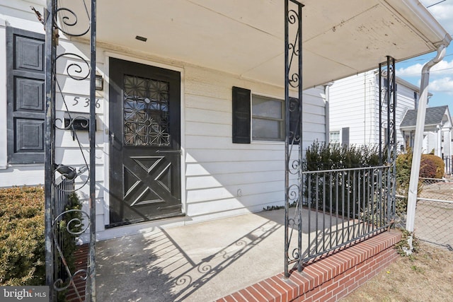 entrance to property with covered porch and fence