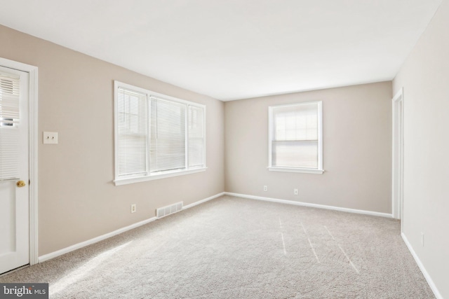 carpeted empty room featuring visible vents and baseboards