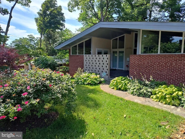 exterior space featuring brick siding and a yard