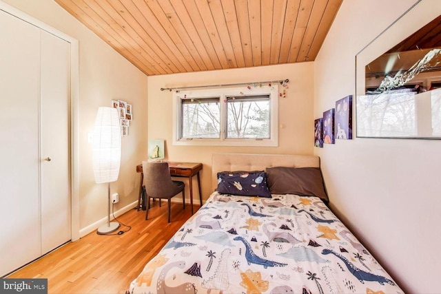 bedroom featuring lofted ceiling, a closet, wood ceiling, wood finished floors, and baseboards