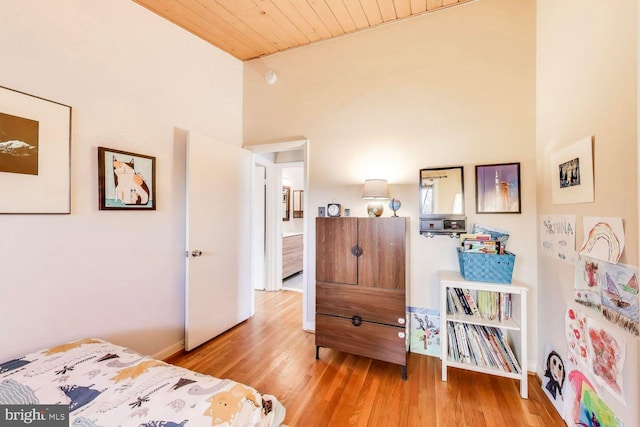 bedroom with high vaulted ceiling, wooden ceiling, baseboards, and wood finished floors