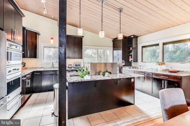 kitchen with a warming drawer, light tile patterned floors, decorative light fixtures, and a center island