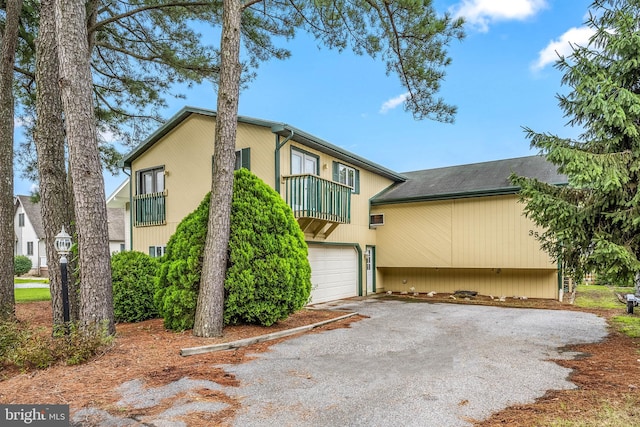 multi unit property with driveway, an attached garage, and a balcony