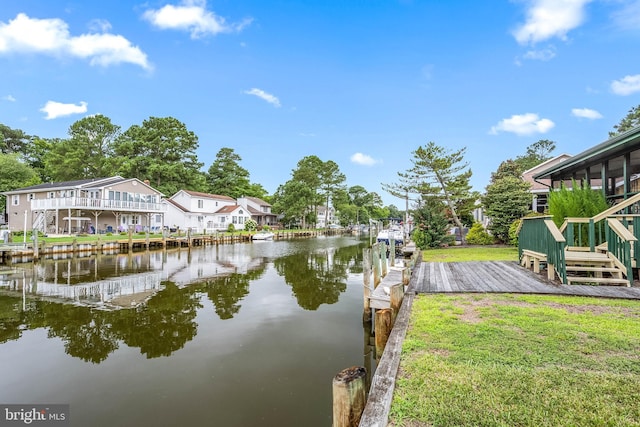 view of dock with a lawn, a water view, and a residential view