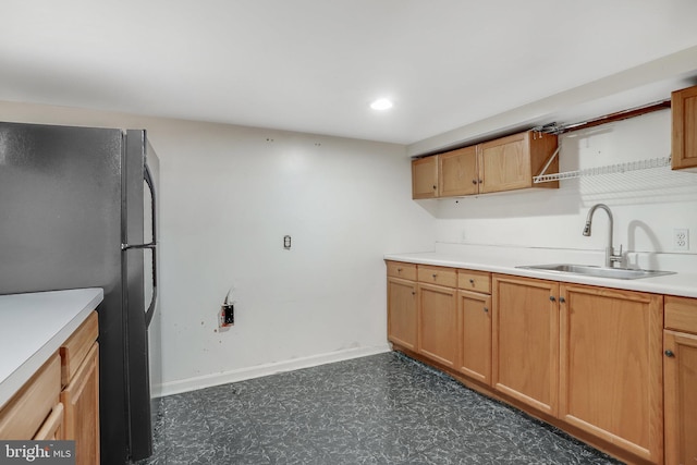 kitchen with light countertops, a sink, and freestanding refrigerator