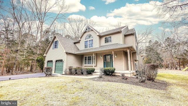 view of front of home with a garage, covered porch, driveway, roof with shingles, and a front yard