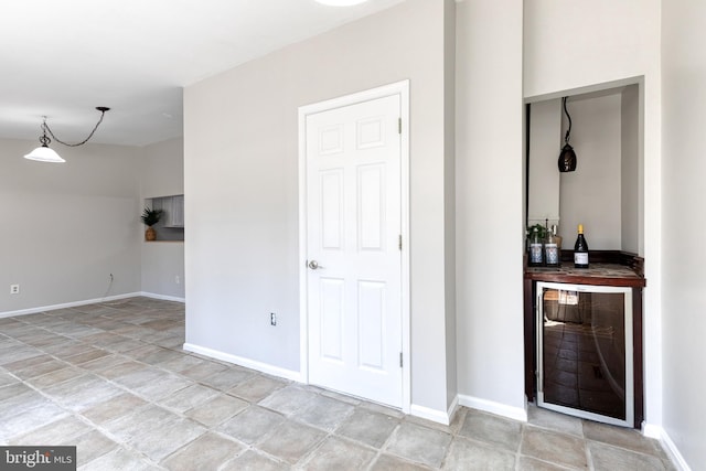 interior space with baseboards, wine cooler, and a bar