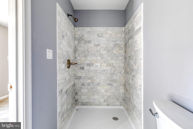 bathroom featuring a tile shower and toilet