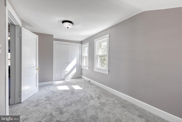 unfurnished bedroom with a closet, vaulted ceiling, baseboards, and carpet floors