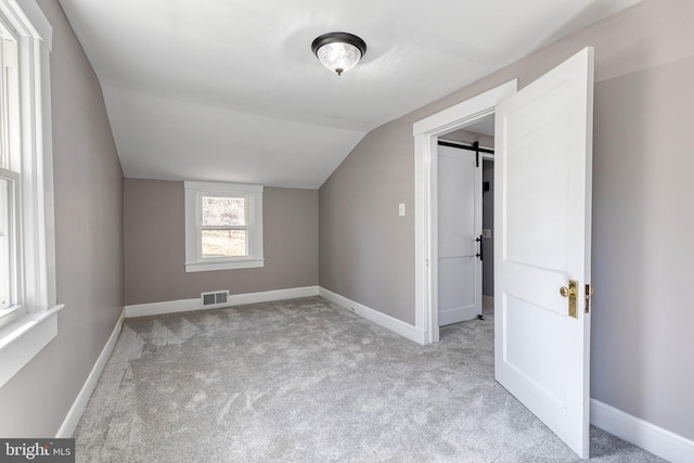 additional living space featuring a barn door, baseboards, and visible vents