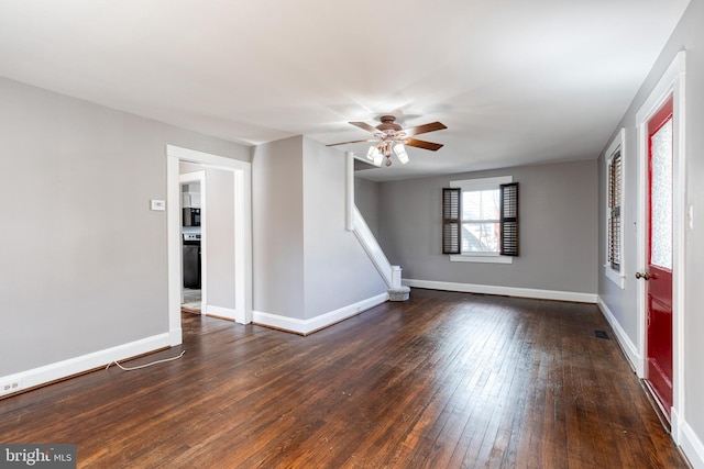 empty room with dark wood finished floors, a ceiling fan, stairs, and baseboards