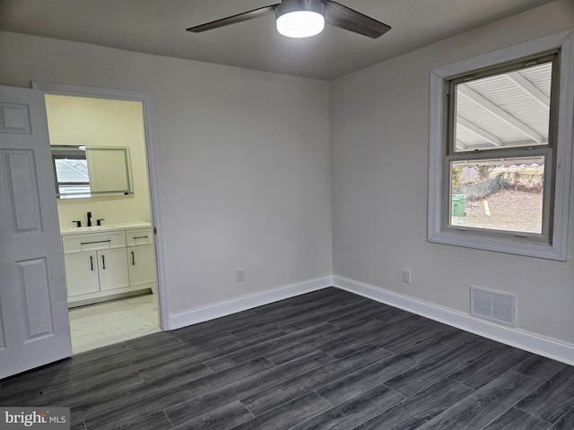 unfurnished bedroom with baseboards, connected bathroom, visible vents, and dark wood-type flooring