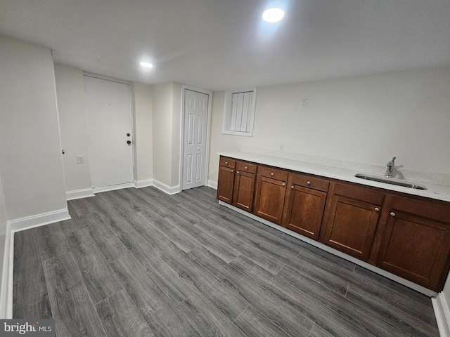 bar featuring wood finished floors, a sink, and baseboards