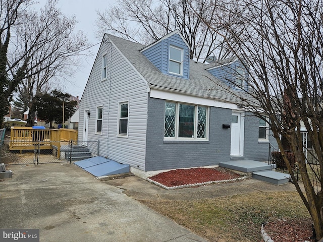 cape cod-style house with a shingled roof and brick siding
