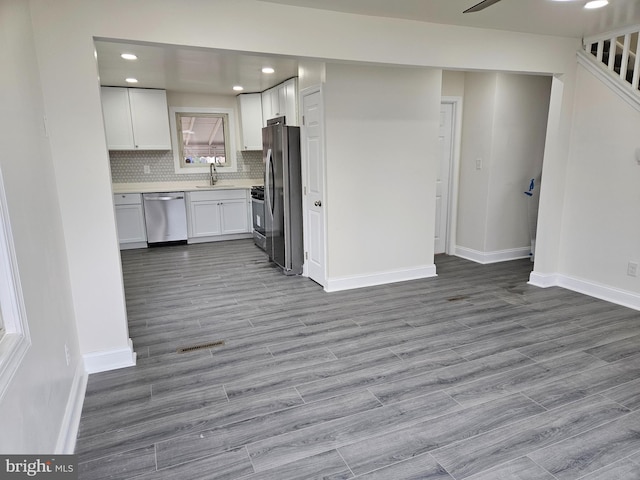 kitchen with stainless steel appliances, a sink, white cabinetry, light countertops, and decorative backsplash