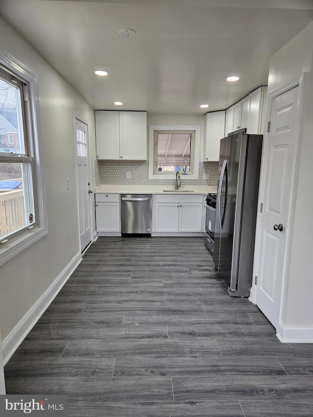 kitchen featuring backsplash, stainless steel appliances, light countertops, white cabinetry, and a sink
