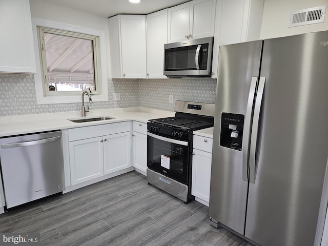 kitchen with stainless steel appliances, a sink, visible vents, white cabinetry, and light countertops