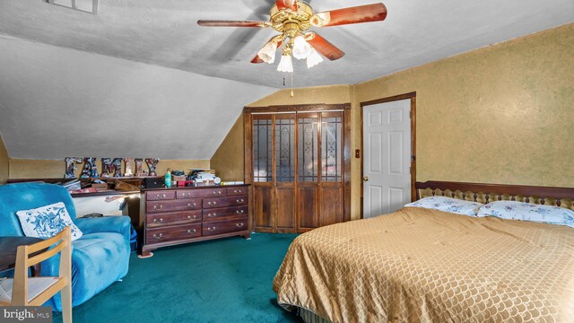 bedroom with lofted ceiling, dark carpet, a ceiling fan, and a textured wall