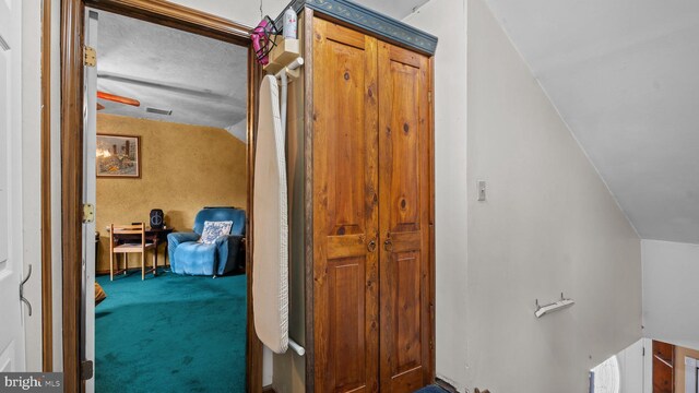 corridor featuring vaulted ceiling and carpet flooring