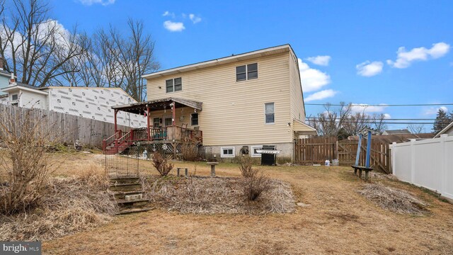 back of property featuring a fenced backyard and stairs