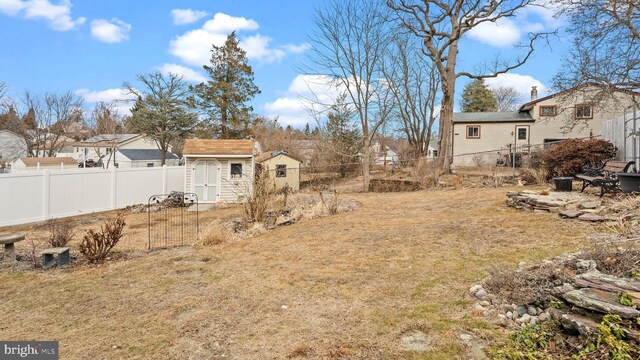 view of yard with a storage shed, a fenced backyard, and an outbuilding