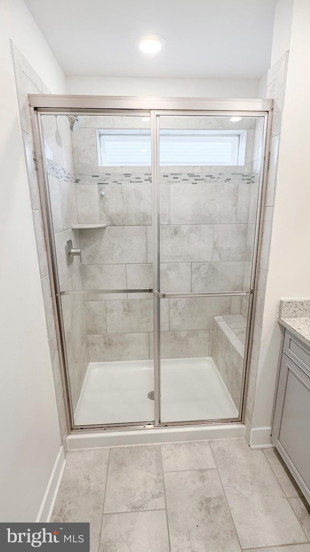 bathroom featuring baseboards, a stall shower, vanity, and a healthy amount of sunlight