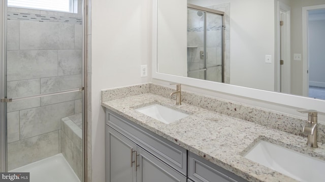 full bathroom featuring double vanity, a stall shower, and a sink