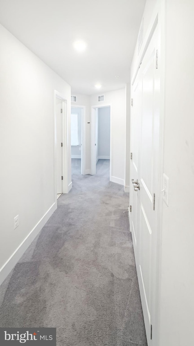 hall featuring carpet floors, visible vents, and baseboards