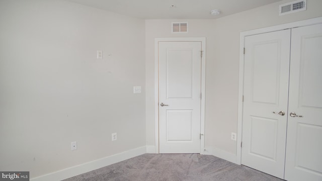 unfurnished bedroom featuring a closet, carpet, visible vents, and baseboards