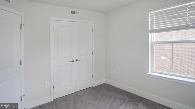 unfurnished bedroom with carpet flooring, a closet, visible vents, and baseboards