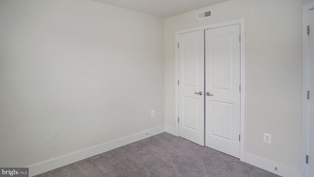 unfurnished bedroom with a closet, baseboards, visible vents, and carpet flooring